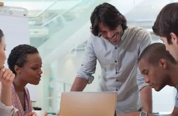 Students gathered around a laptop having a discussion