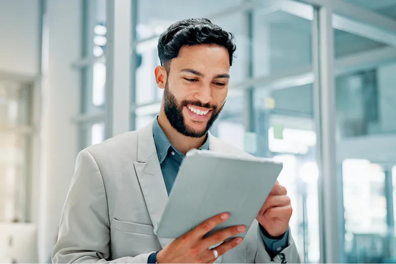 Young man wearing a blazer looking at investing options on his tablet device