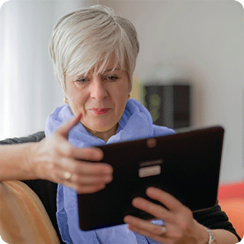 Retiree online looking at screen on a tablet she is holding